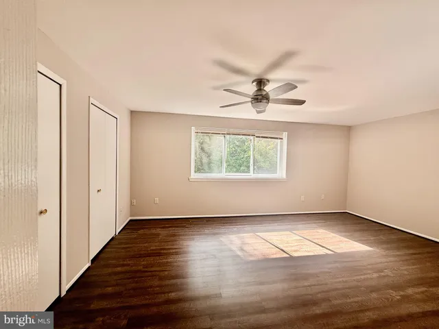 an empty room with wooden floor chandelier fan and windows