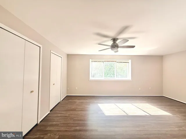 an empty room with wooden floor fan and windows