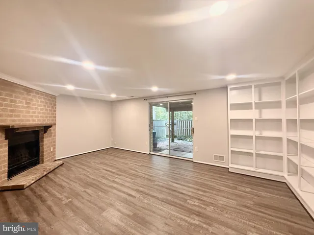 an empty room with wooden floor fireplace and windows