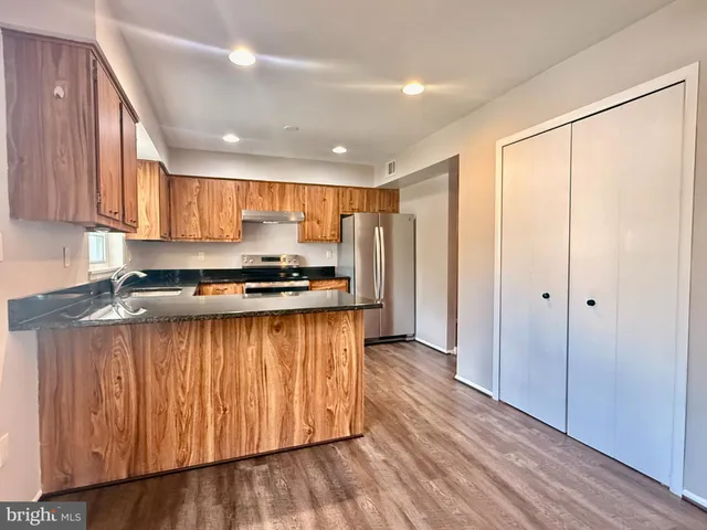 a kitchen with stainless steel appliances granite countertop a refrigerator and a stove top oven