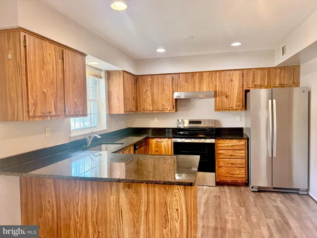a kitchen with granite countertop a refrigerator and a sink