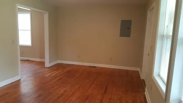 an empty room with wooden floor and windows