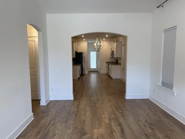 a view of a room with wooden floor staircase and a hallway