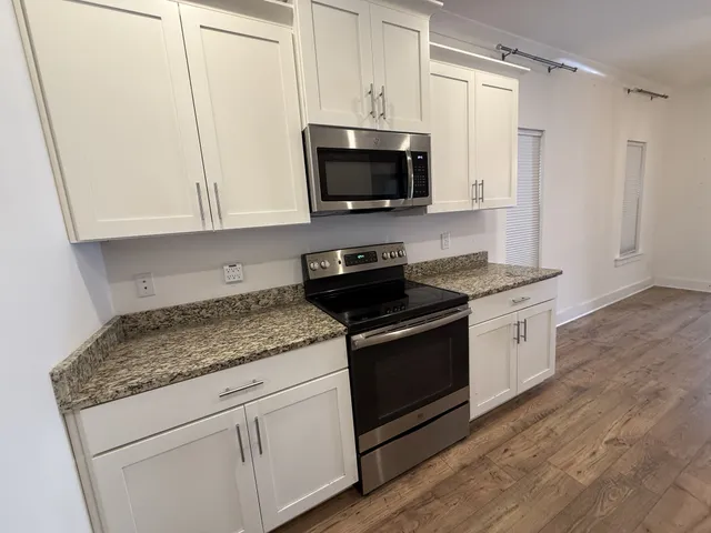 a kitchen with stainless steel appliances granite countertop a stove a microwave and a white cabinets