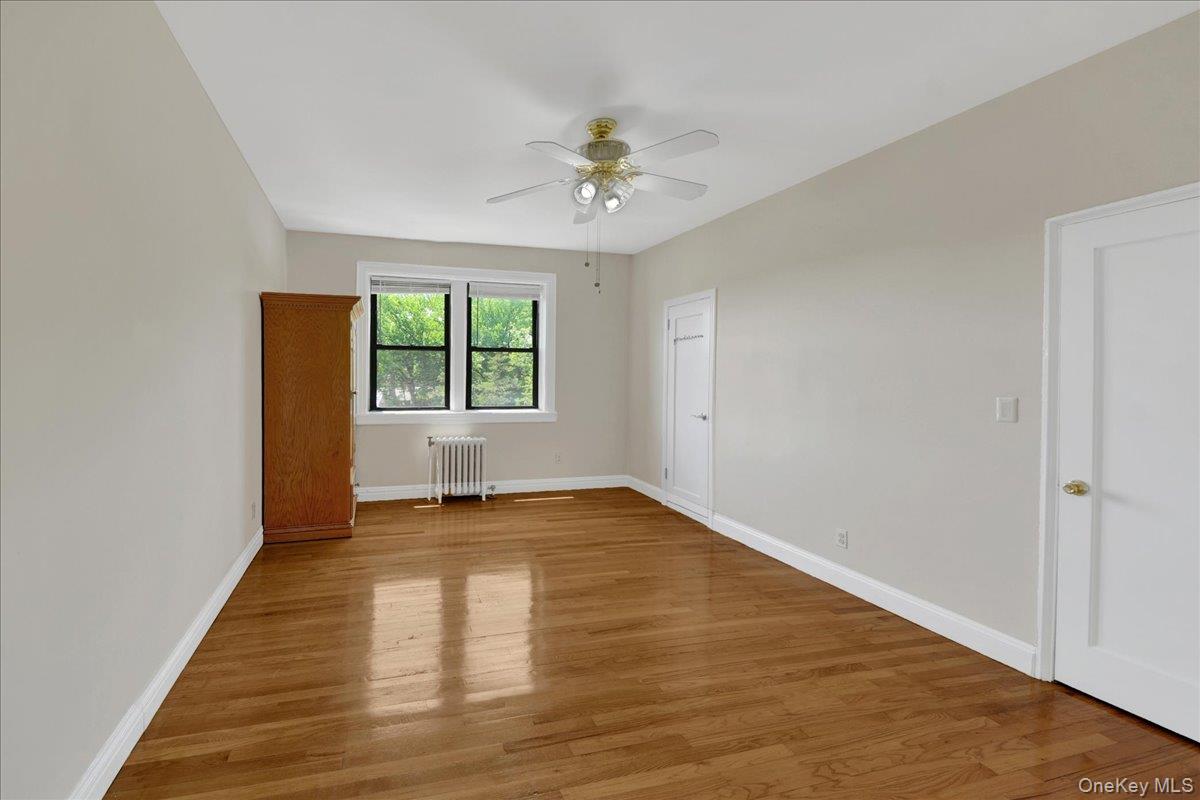 4784 Boston Post Road, Unit B43 Pelham, NY 10803 - Photo 8 of 22 an empty room with wooden floor chandelier fan and windows
