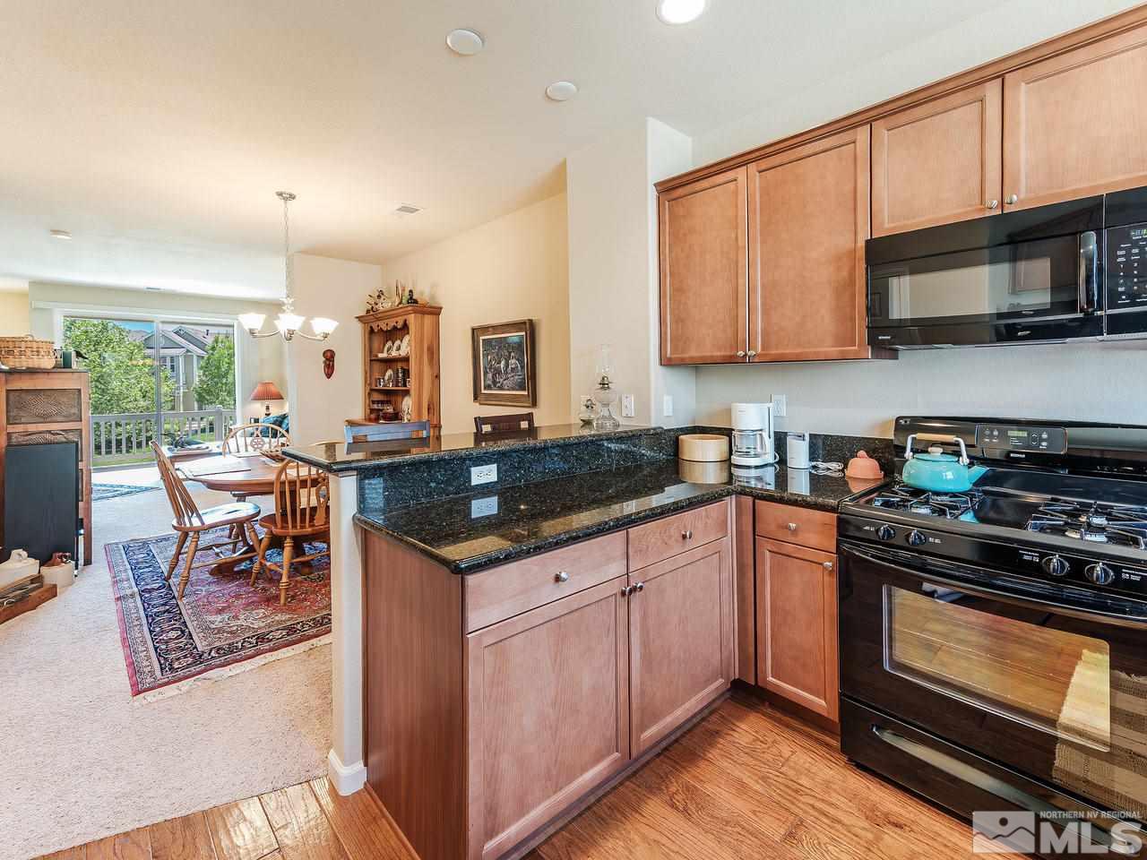 240 Gramercy Lane Reno, NV 89509 - Photo 6 of 18 a kitchen with stainless steel appliances granite countertop a stove top oven a sink dishwasher a dining table and chairs with wooden floor