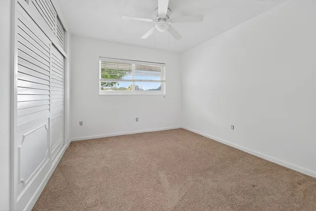 an empty room with windows and ceiling fan