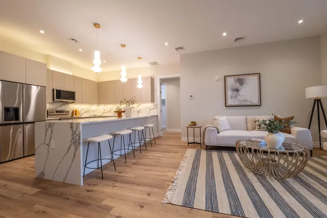 a large kitchen with kitchen island a large counter top space a sink stainless steel appliances and cabinets