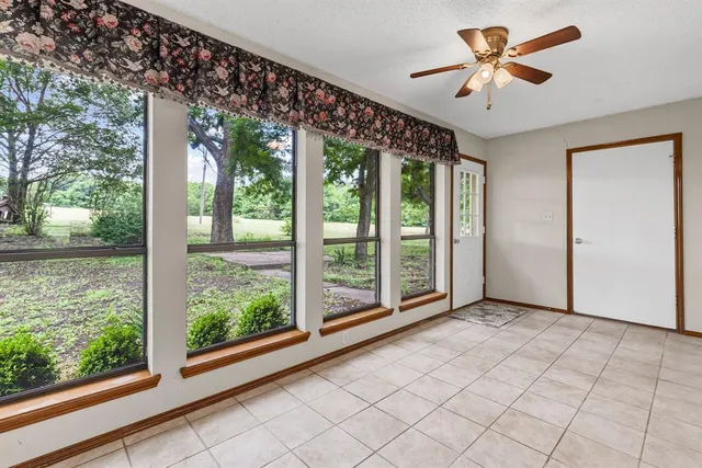 an empty room with wooden floor chandelier fan and windows