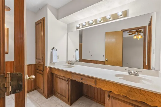 an empty room with wooden floor chandelier fan and windows