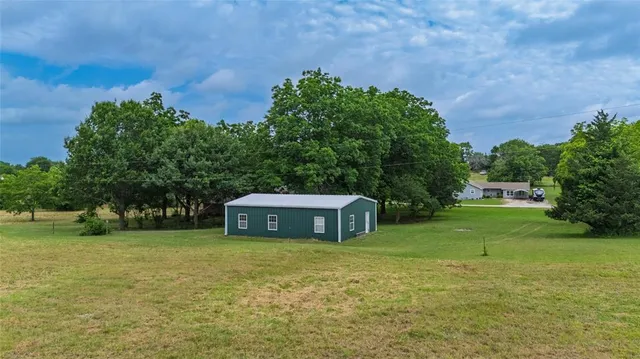 an aerial view of residential houses with outdoor space and trees