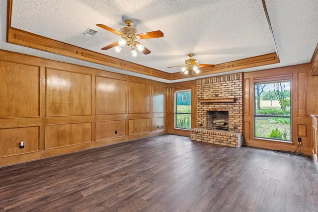 a view of an empty room with wooden floor fireplace and a window