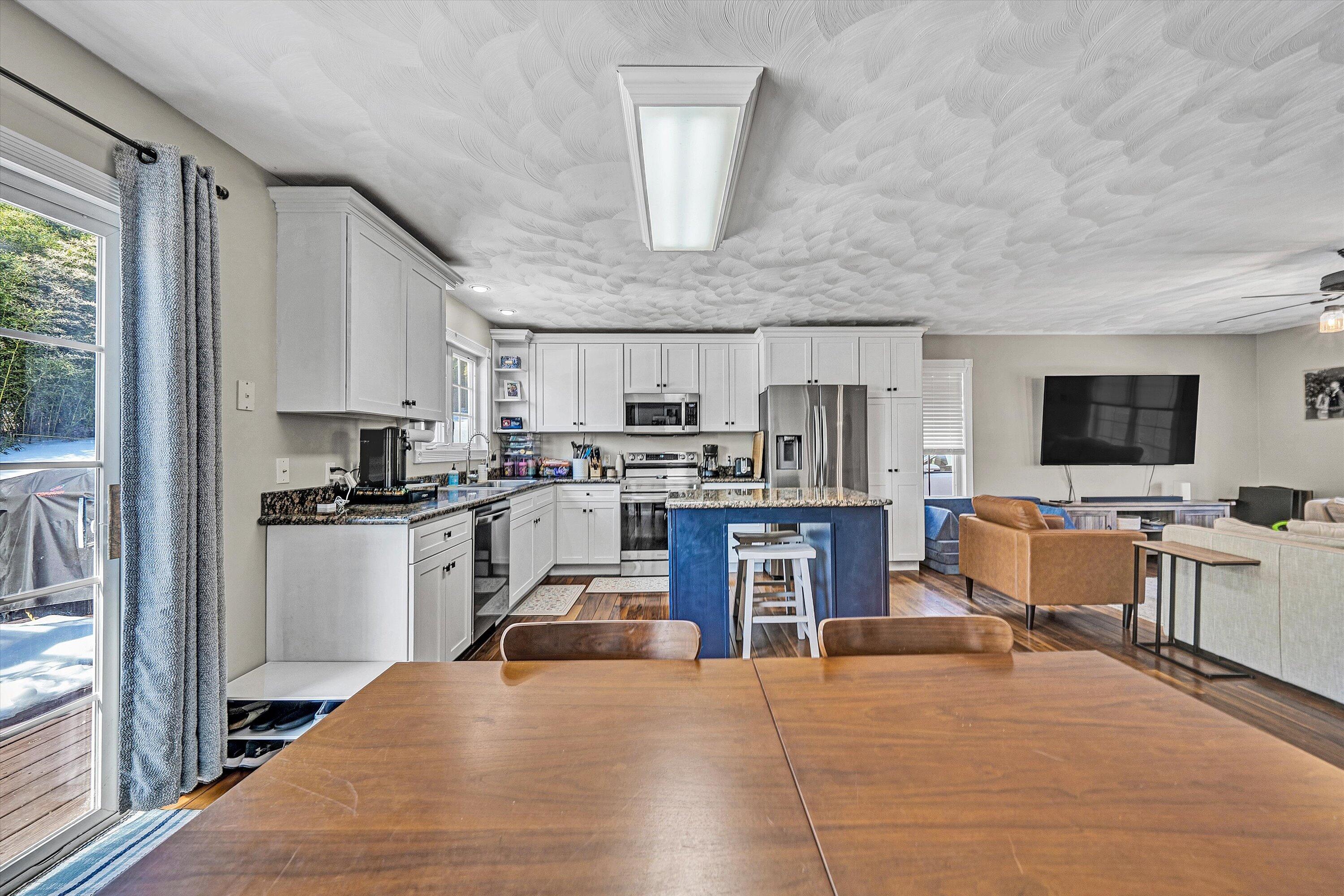 409 Wills Road Lexington, VA 24450 - Photo 10 of 42 a kitchen with stainless steel appliances kitchen island granite countertop a stove top oven a sink dishwasher a dining table and chairs with wooden floor