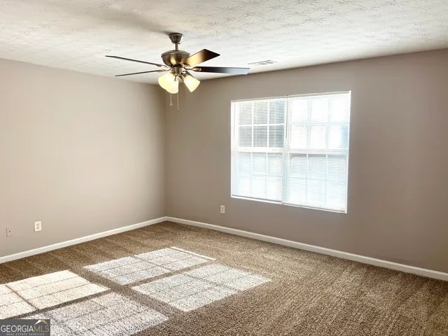 an empty room with windows and fan