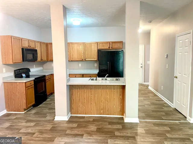 a living room with stainless steel appliances kitchen island granite countertop a refrigerator stove and sink
