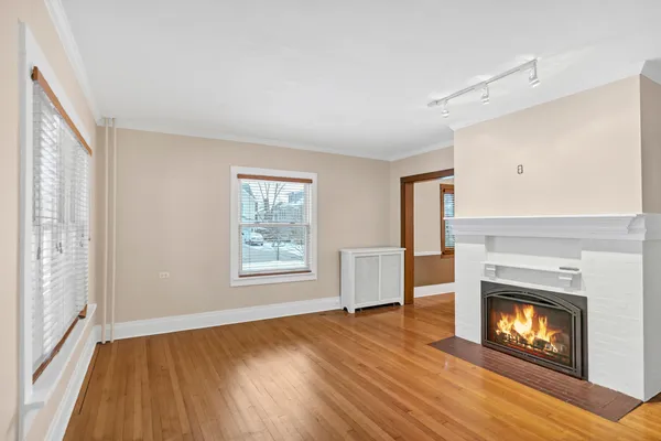 a view of an empty room with wooden floor fireplace and a window