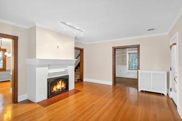 a view of an empty room with wooden floor fireplace and a window