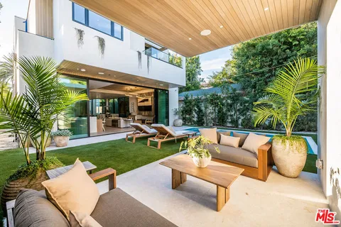 a view of a patio with couches and a table and chairs with plants and wooden fence