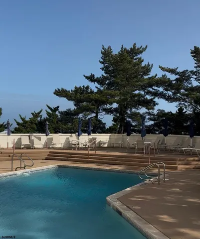 a view of swimming pool with outdoor seating and trees in the background