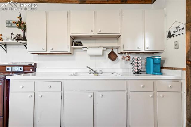616 Timber Ridge Road Divide, CO 80814 - Photo 10 of 34 Kitchen with light countertops, open shelves, a sink, and range