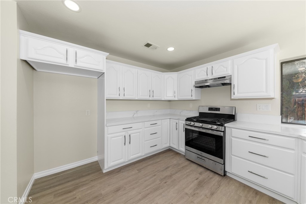 32465 Cape Cod Drive Lake Elsinore, CA 92530 - Photo 12 of 29 a kitchen with white cabinets and stainless steel appliances