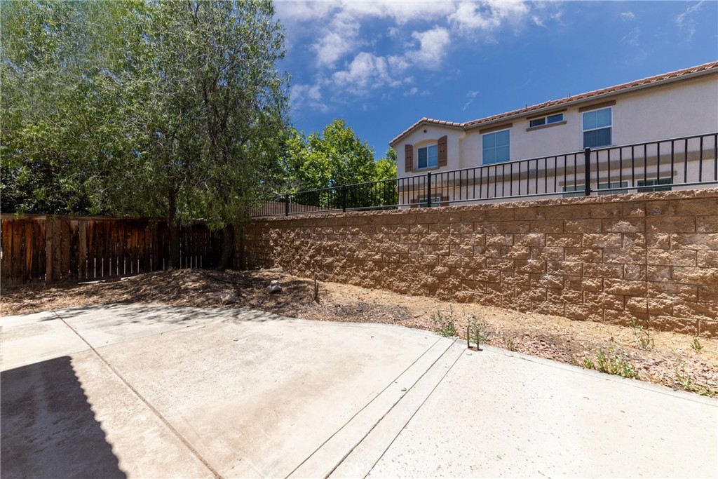 32465 Cape Cod Drive Lake Elsinore, CA 92530 - Photo 28 of 29 a backyard of a house with large trees and wooden fence