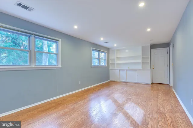 a view of an empty room with a window and wooden floor