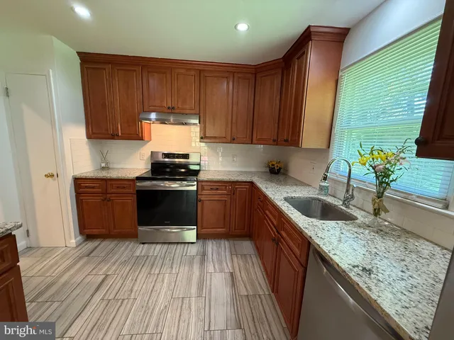 a kitchen with granite countertop wooden cabinets a stove and a sink
