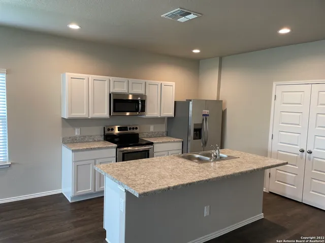 a kitchen with granite countertop a refrigerator and a stove top oven