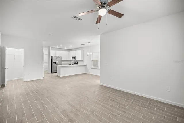 an empty room with a ceiling fan and carpet