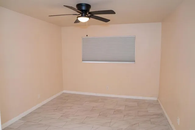 an empty room with a window and a ceiling fan