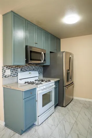 a kitchen with stainless steel appliances granite countertop a stove a refrigerator and a microwave
