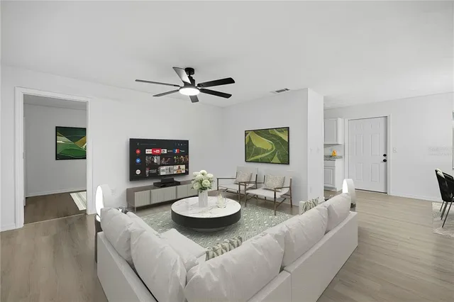 a living room with furniture a flat screen tv and a dining table with wooden floor