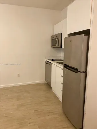 a view of a refrigerator in kitchen and white cabinets