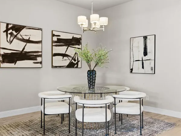 a kitchen with a dining table chairs wooden floor appliances and cabinets