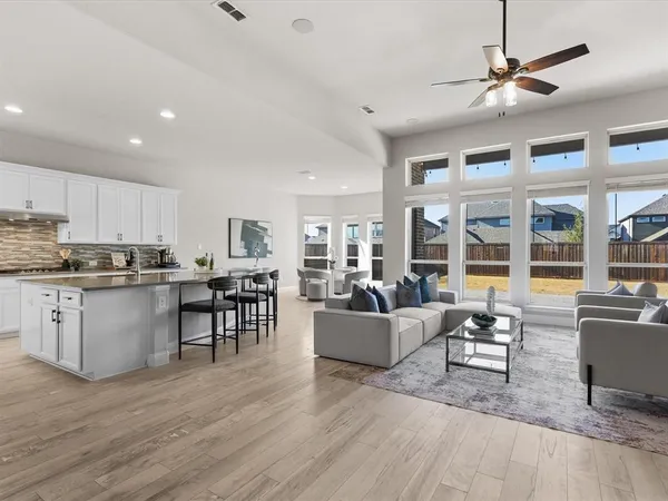 a living room with furniture kitchen view and a wooden floor