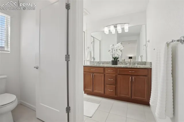 a bathroom with a granite countertop sink a toilet and a mirror