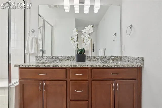 a bathroom with a granite countertop sink a mirror and a shower