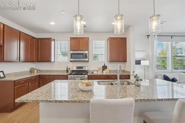 a kitchen with granite countertop a sink a counter top space cabinets and stainless steel appliances