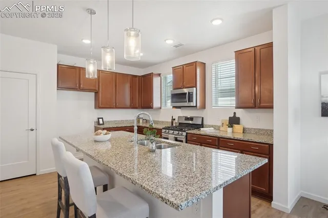 a kitchen with granite countertop a sink a counter space appliances and cabinets