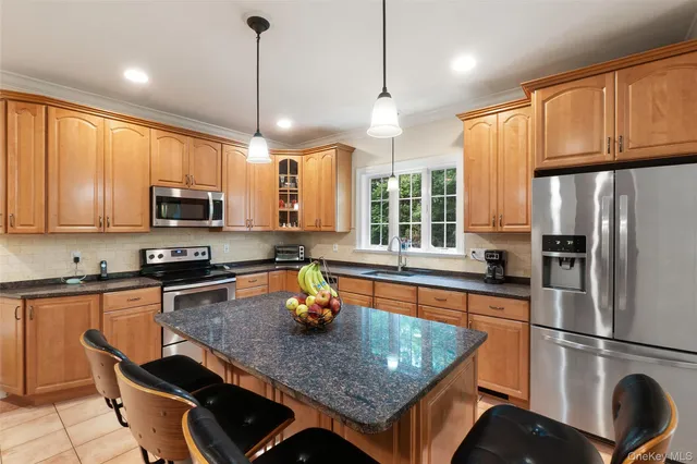 a kitchen with stainless steel appliances granite countertop a sink a stove a refrigerator cabinets and chairs