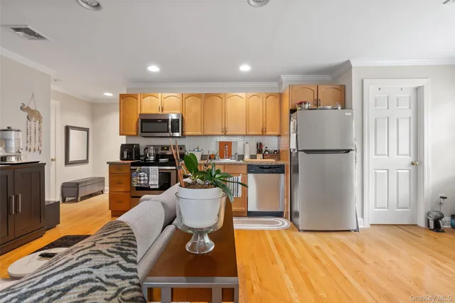 a kitchen with stainless steel appliances granite countertop a refrigerator a stove a sink a dining table and chairs with wooden floor