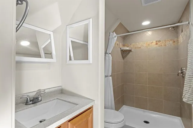 a bathroom with a sink vanity granite toilet and shower