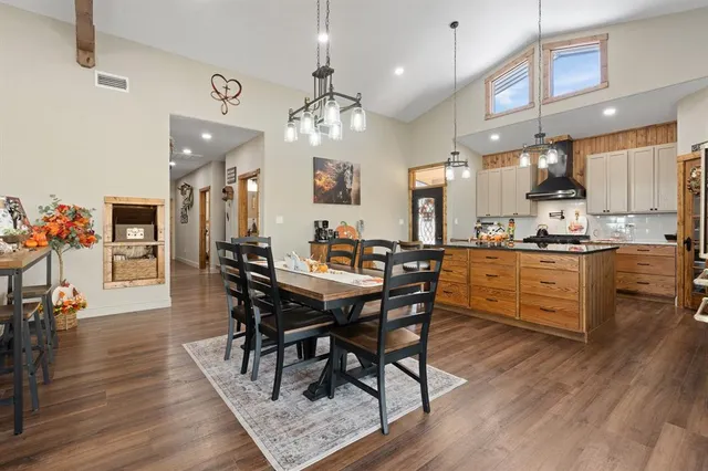 a kitchen with stainless steel appliances kitchen island granite countertop a table chairs and a refrigerator