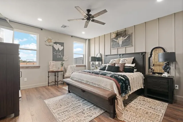 a bedroom with a bed and a dresser with wooden floor