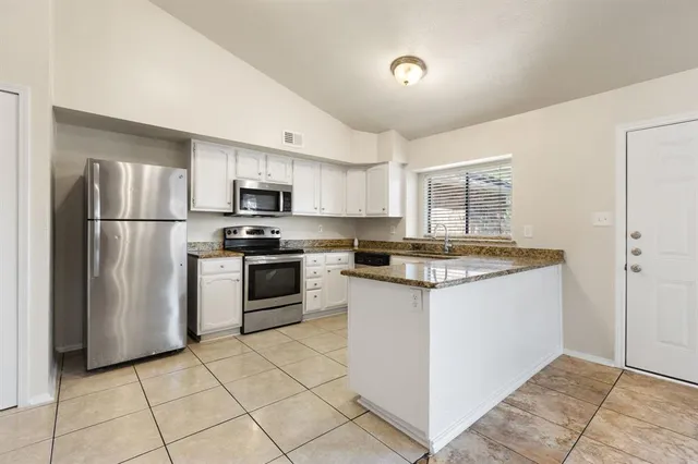 a kitchen with granite countertop a refrigerator and a stove top oven