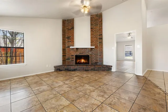 a view of an empty room with fireplace and a window