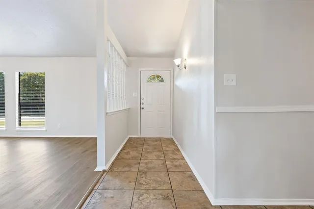 a view of a hallway with wooden floor and a bathroom