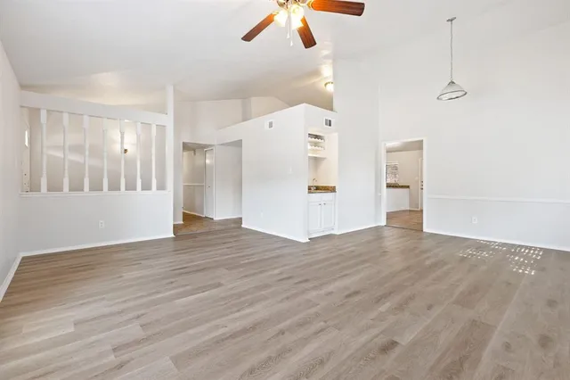 a view of an empty room with wooden floor and a ceiling fan