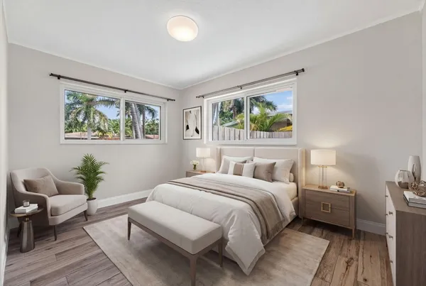 a bedroom with a large bed a potted plant and a window